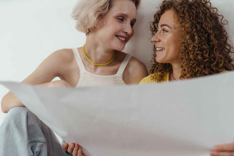 Pareja sonriente mirándose mientras sostiene una hoja de papel